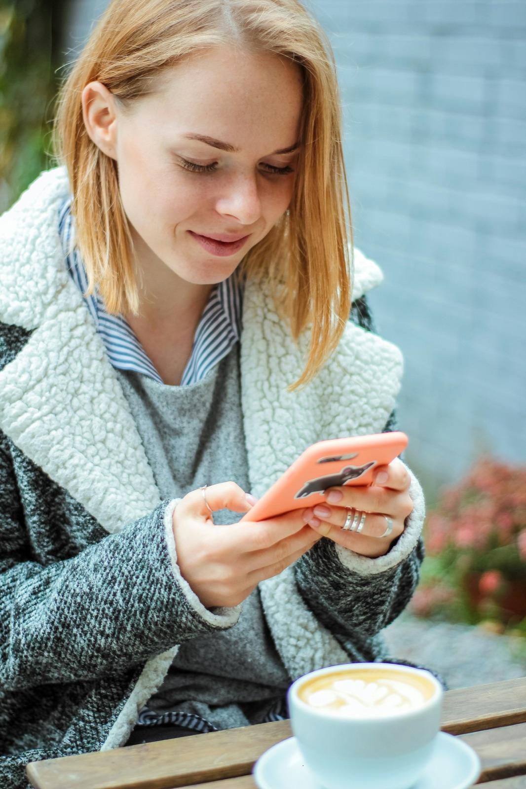 A woman smiling at a message on her phone
